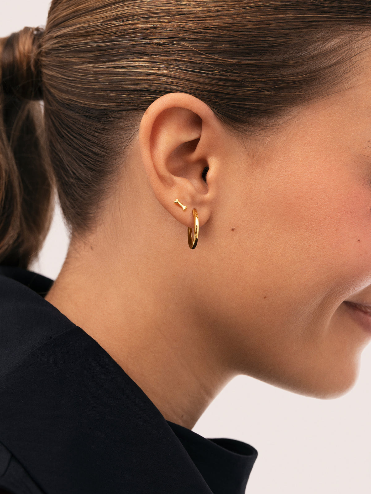 Einzelner Ohrring Mini-Knochen aus Silber, vergoldet - puesto en modelo